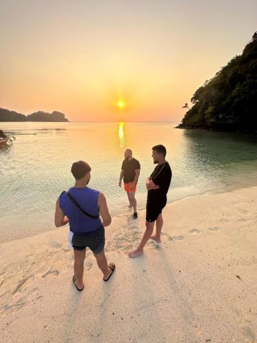 three men walking on the beach at sunset at Angthong Beach Resort in Koh Phaluai