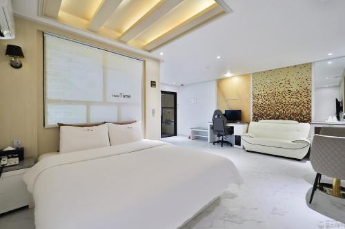 a bedroom with a large white bed and a desk at Time Hotel in Yangsan