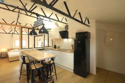 Il comprend une cuisine équipée d'une table et d'un réfrigérateur noir. dans l'établissement Original Loft, à Bages