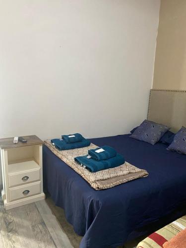 a bed with blue pillows on it with a night stand at Caralíhome in Esquina