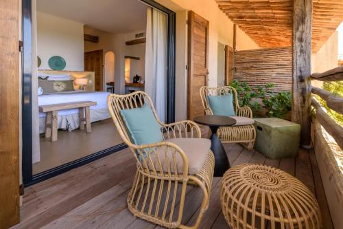 a bedroom with a bed and chairs on a deck at Les Bergeries De Palombaggia in Porto-Vecchio