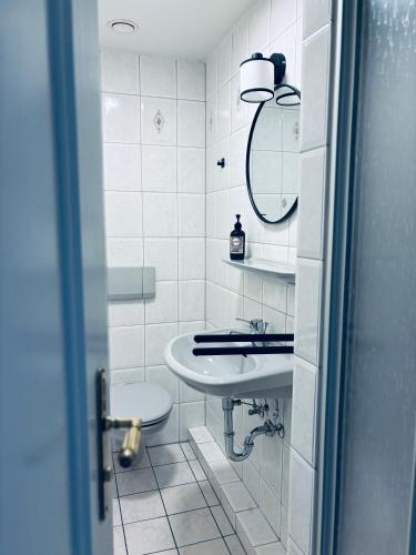 a white bathroom with a sink and a mirror at Hotel Thesdorfer Hof in Pinneberg