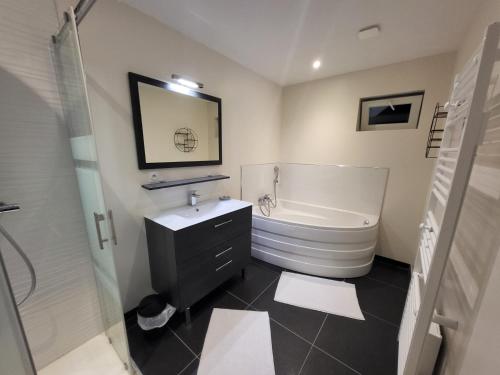 a bathroom with a white tub and a sink and a toilet at La marine D'opale in Ambleteuse