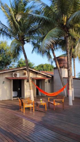 a hammock in front of a building with palm trees at Pousada Piraúna in Fernando de Noronha