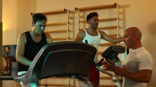 two men on a treadmill while another man is talking to another man at Hotel Casale in Colli del Tronto