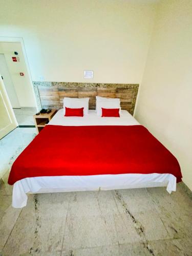 a bedroom with a large bed with a red blanket at Alvorada Palace Hotel de Poços in Poços de Caldas