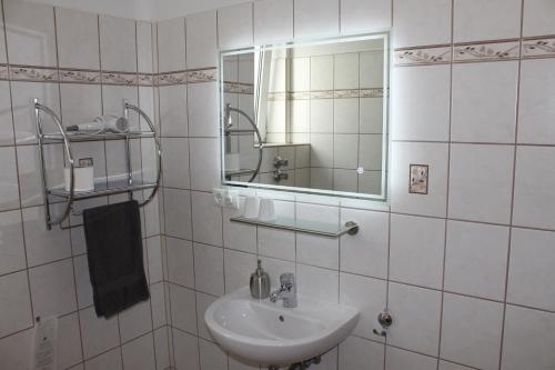 a white bathroom with a sink and a mirror at TOTO's Gasthaus in Hattingen