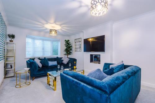 a living room with two blue couches and a tv at Kinship House by YourStays - Stunning Holiday Home in the Suburbs in Newcastle under Lyme
