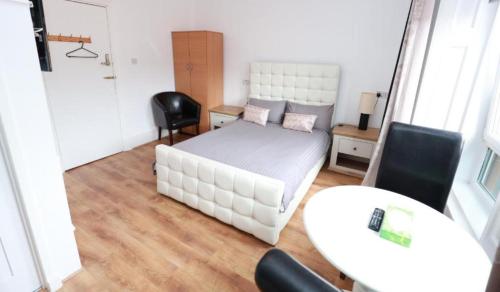 a bedroom with a white bed and a table and chairs at Glasgow South Studio in Glasgow