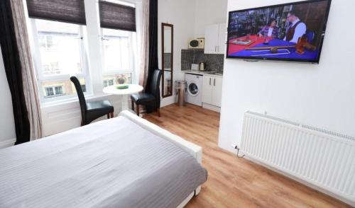 a bedroom with a bed and a tv on a wall at Glasgow South Studio in Glasgow