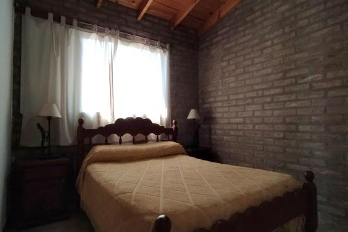 a bedroom with a bed and a brick wall at Cabañas MACONDO in Villa Ciudad Parque