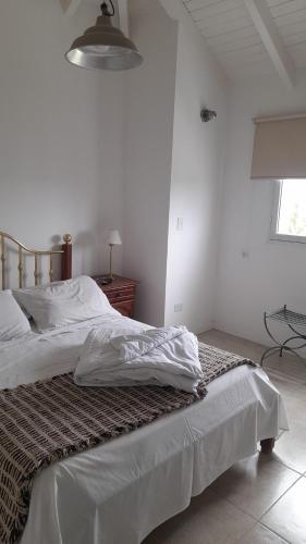 a bedroom with a bed with white sheets on it at BarrancasdelGolfo in Puerto Madryn