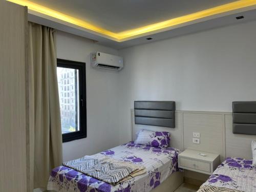 a bedroom with two beds and a window at Stylish 2-Bedroom Apartment in Celia Compound, New Administrative Capital in Madīnat al Amal