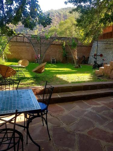 a patio with a table and chairs in a yard at KASBAH Jardin des délices Timalizen in Tamzerdirt