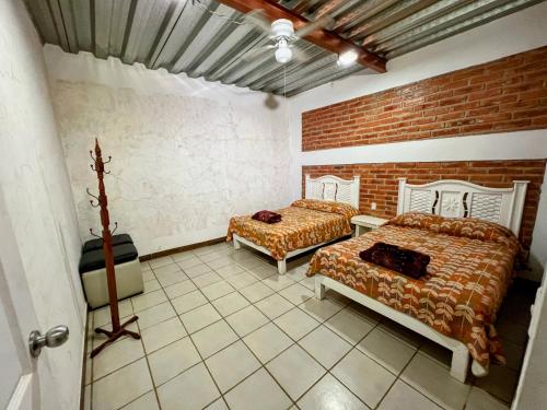 a bedroom with two beds and a brick wall at Rancho El Venado Termales in Acatic