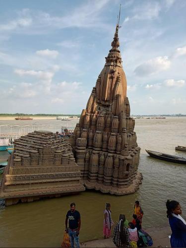 a large building in the water with people standing around it at Pushkarni Home Stay in Varanasi