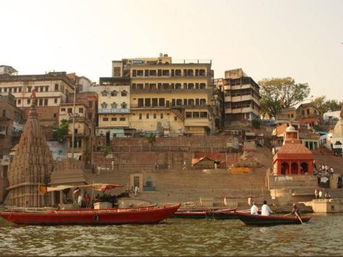 a group of boats in the water near a city at Pushkarni Home Stay in Varanasi