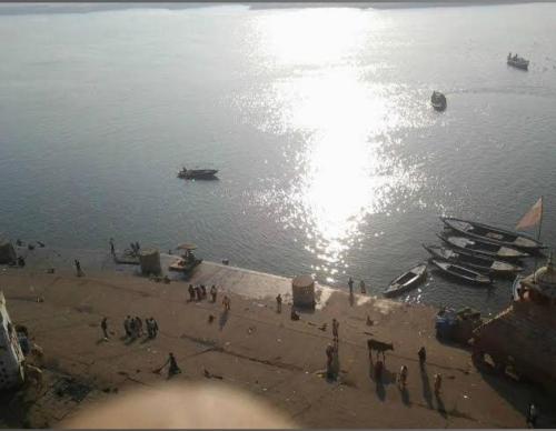 a group of people standing on a beach near the water at Pushkarni Home Stay in Varanasi