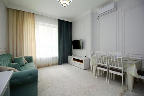 Una sala de estar con un sofá, una mesa y un televisor. en Central Avenue, en Almaty