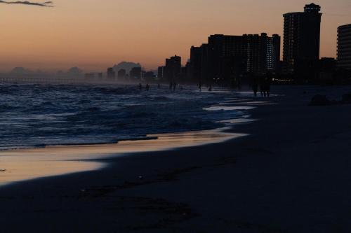 people walking on the beach at sunset at COUPLES GETAWAY, HONEYMOON SWEET, Perfectly Cozy Beach Front Condo with kitchen, pool, free parking,CHECK-IN AT DOOR in Panama City Beach