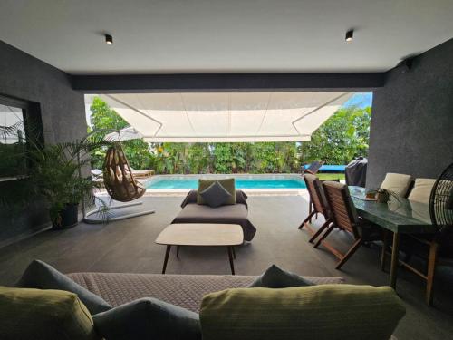 a living room with a couch and a table and a pool at TG NEW Luxury Private Resort & SPA Villas - Heated Salty Swimming Pool, Outdoor Jacuzzi, Sauna, Exotic Garden in Limassol
