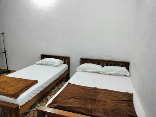 zwei Betten in einem Zimmer mit weißen Wänden in der Unterkunft Hill garden homestay,Vagamon in Vagamon