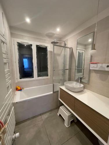 une salle de bain avec un lavabo et une baignoire et un lavabo dans l'établissement Le cocon du Parisis, à Cormeilles-en-Parisis