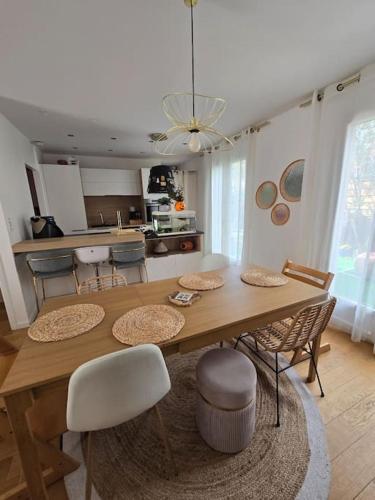une cuisine et une salle à manger avec une table et des chaises en bois dans l'établissement Le cocon du Parisis, à Cormeilles-en-Parisis