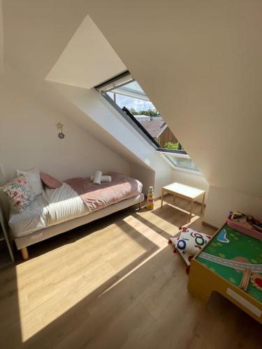 une chambre mansardée avec un lit et une fenêtre dans l'établissement Le cocon du Parisis, à Cormeilles-en-Parisis