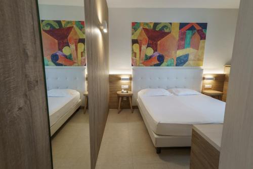 two beds in a room with paintings on the walls at Hotel Morgana in Mendrisio