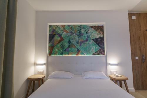a bedroom with a bed with a painting above it at Hotel Morgana in Mendrisio