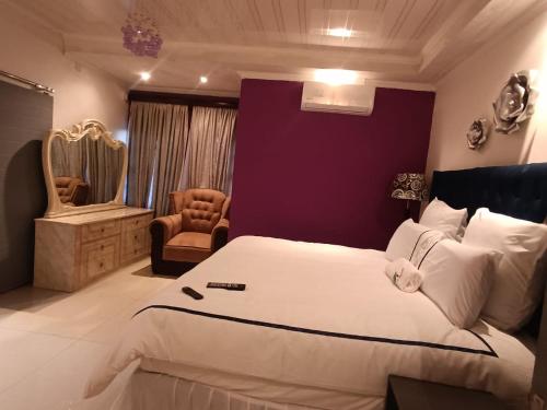 a bedroom with a large white bed and a chair at Manasseh Bed & BreakFast Gabs North in Kgaphamadi