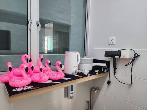 a group of pink flamingos sitting on a shelf in a bathroom at Cozy FamiLee Homestay in Simpang Ampat
