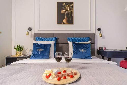 a bed with two glasses of wine and food on it at Lumina I Premium Apartments with Balcony I Parking I Pasaż Łódzki in Łódź