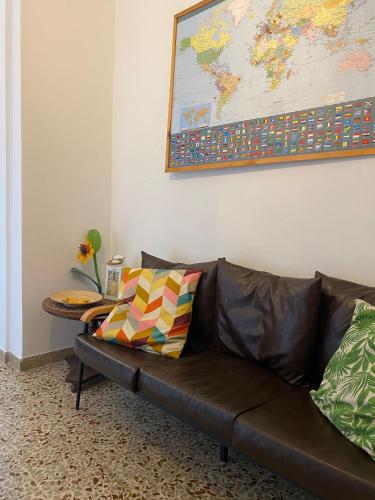a brown leather couch with a table and a map on the wall at APPARTAMENTO LA SPIAGGETTA in Foligno