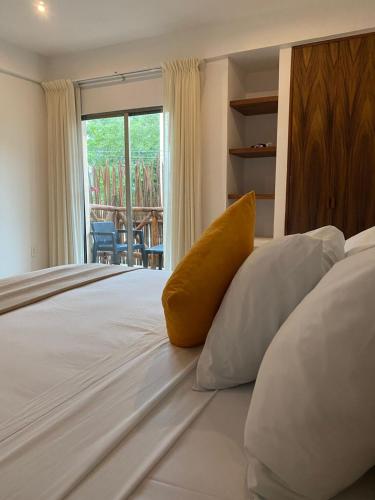 a large white bed with a yellow pillow on it at Hotel Pelecanus Suites Holbox in Holbox Island