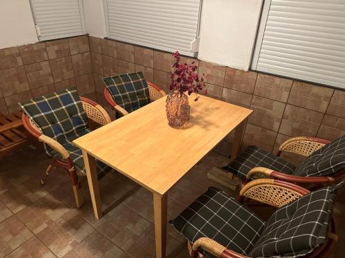 a wooden table with chairs and a vase with flowers on it at Apartments Marja in Slovenj Gradec