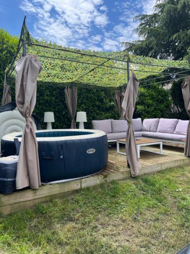 un jacuzzi dans une cour avec un canapé et une table dans l'établissement Écrin de verdure, à La Tour-de-Salvagny