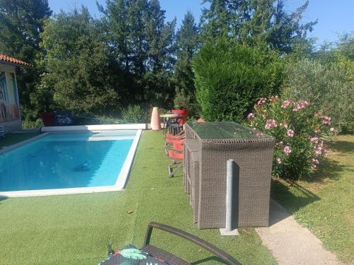 a wicker chair and a trash can next to a pool at Villa Provençale avec Spa Piscine Privée in Ris