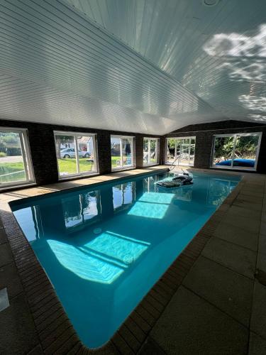 a large swimming pool in a building with windows at Little Eden New Forest and Coastal Retreat Langley Hampshire in Langley