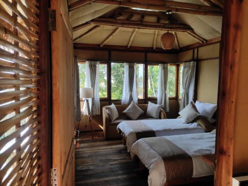two beds in a room with windows at Art Mile Kalimpong in Kalimpong