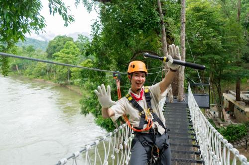 a man on a suspension bridge over a river at Puprai Tarnnarm Resort in Thong Pha Phum