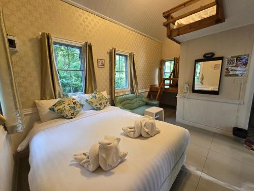 a bedroom with a large white bed with towels on it at Puprai Tarnnarm Resort in Thong Pha Phum