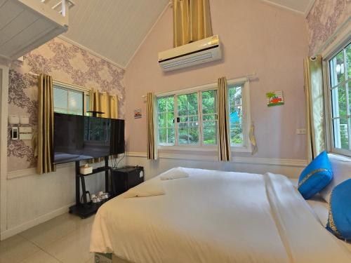 a bedroom with a white bed and a flat screen tv at Puprai Tarnnarm Resort in Thong Pha Phum