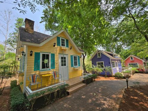 a small yellow house with a porch and a purple house at Puprai Tarnnarm Resort in Thong Pha Phum