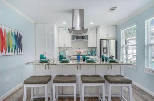 a kitchen with white cabinets and a counter with stools at Island Dreams Oasis Galveston Retreat in Galveston