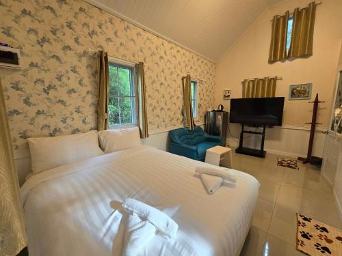 a bedroom with a large white bed and a tv at Puprai Tarnnarm Resort in Thong Pha Phum
