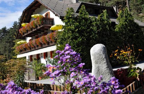 a house with flowers in front of it at Residence Obermoarhof - Family Apartments with Pool & Playground in Vandoies