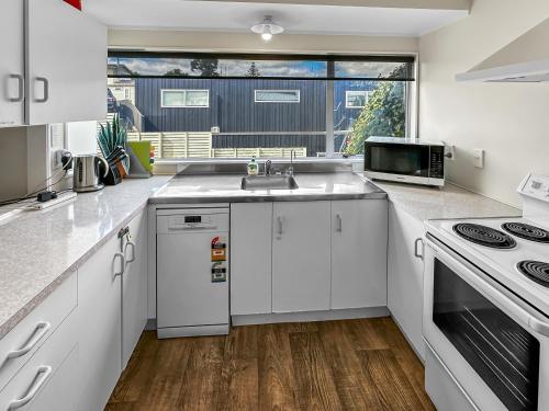 a kitchen with white cabinets and a sink and a window at Onehunga Oasis l 2bed Private Home l Cornwall Park in Auckland