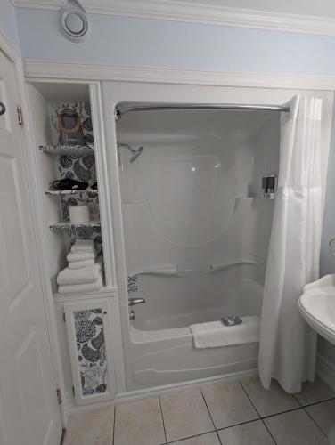 a white bathroom with a shower and a sink at The Parrsboro Mansion Inn in Parrsboro